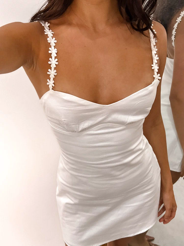 Close-up of the white mini dress showing the sweetheart neckline and delicate daisy chain shoulder straps
