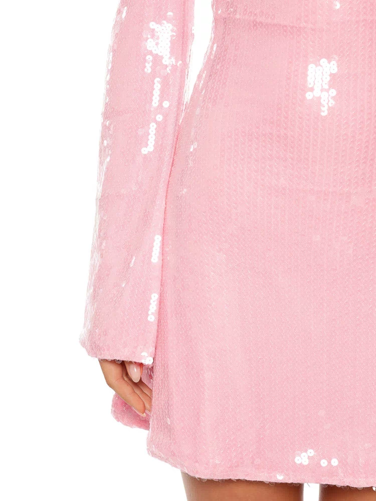A close-up of a light pink mini-dress covered in shimmering sequins highlighting the long bell sleeve and the hemline.