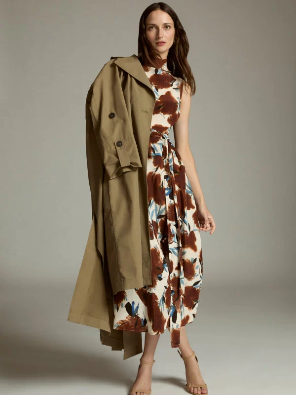 Woman wearing a floral dress with a long green coat against a neutral background | Exclude