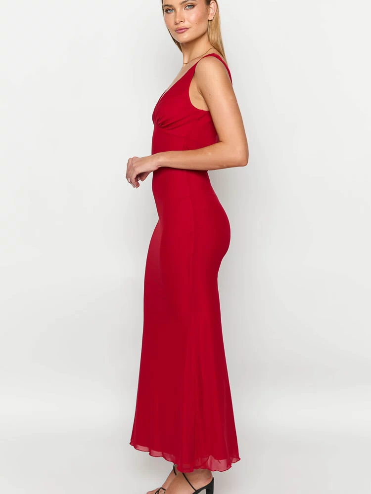 Side view of a red maxi dress with a ruched V-neckline, fitted bodice, and flowy skirt with a sheer hem