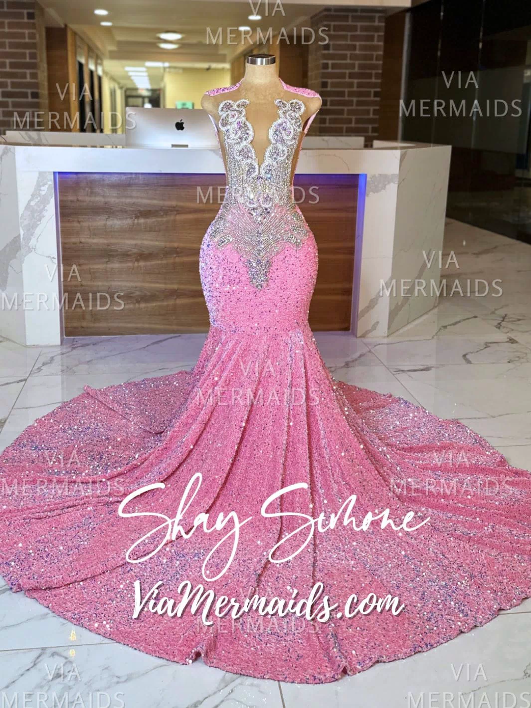 Full image of a mannequin wearing a floor-length iridescent pink sequin mermaid gown with intricate rhinestone details.