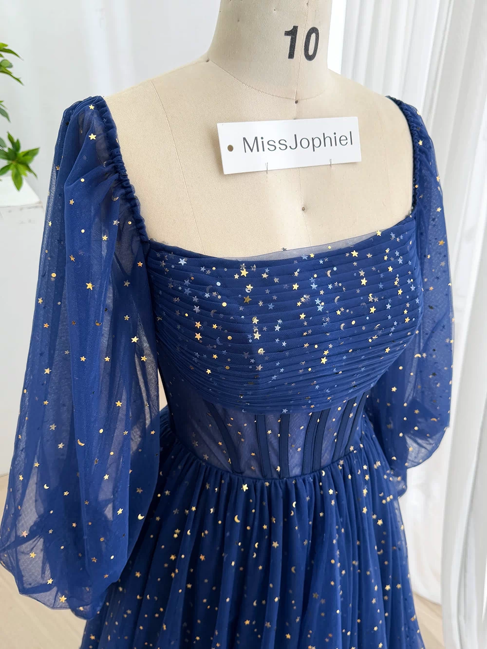 Close frontal portrait of sapphire starry prom attire featuring ruched neckline, transparent corset panels, structured waist.