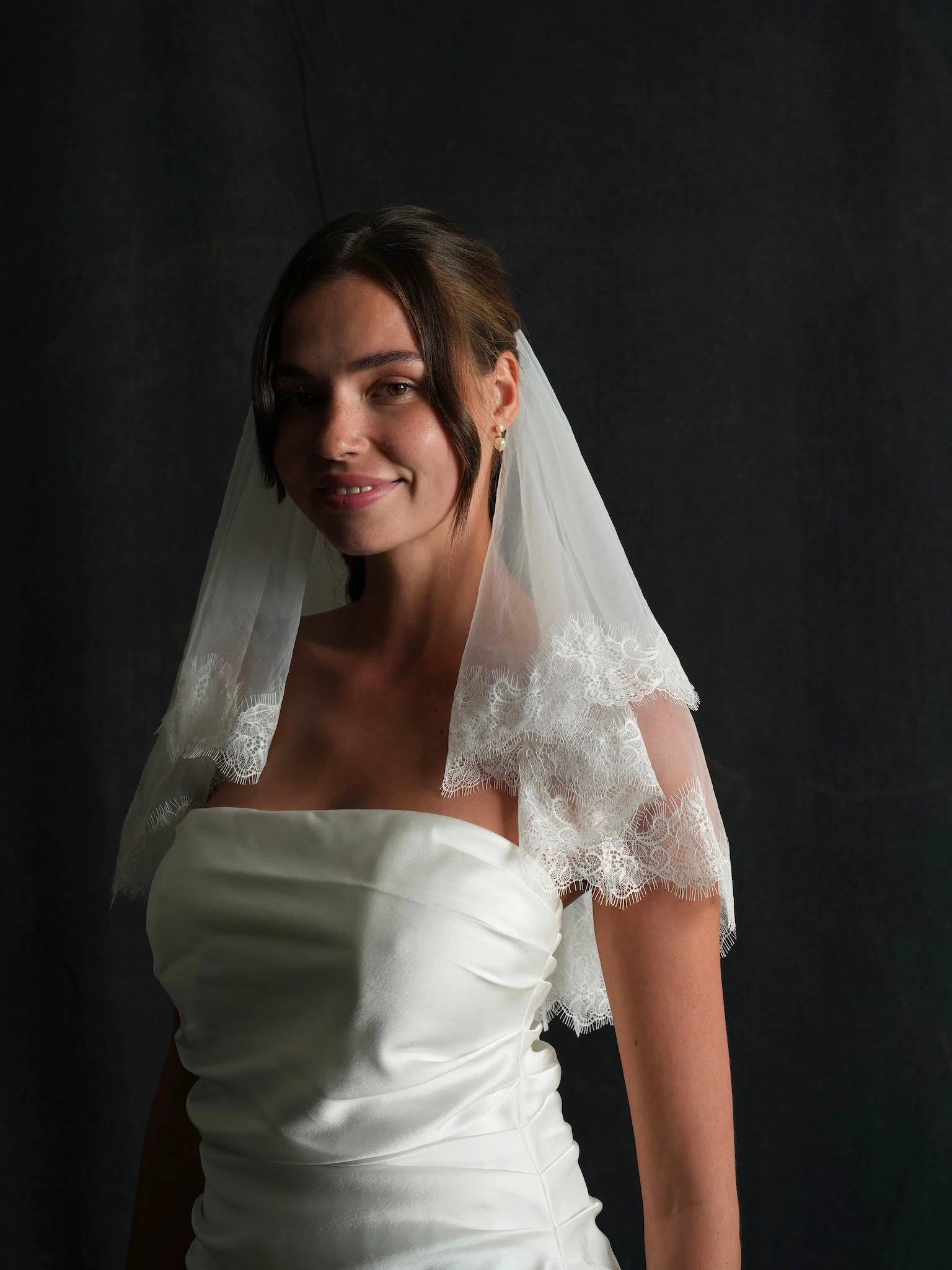 Woman wearing a white wedding dress with a mini lace short two tier bachelorette veil 