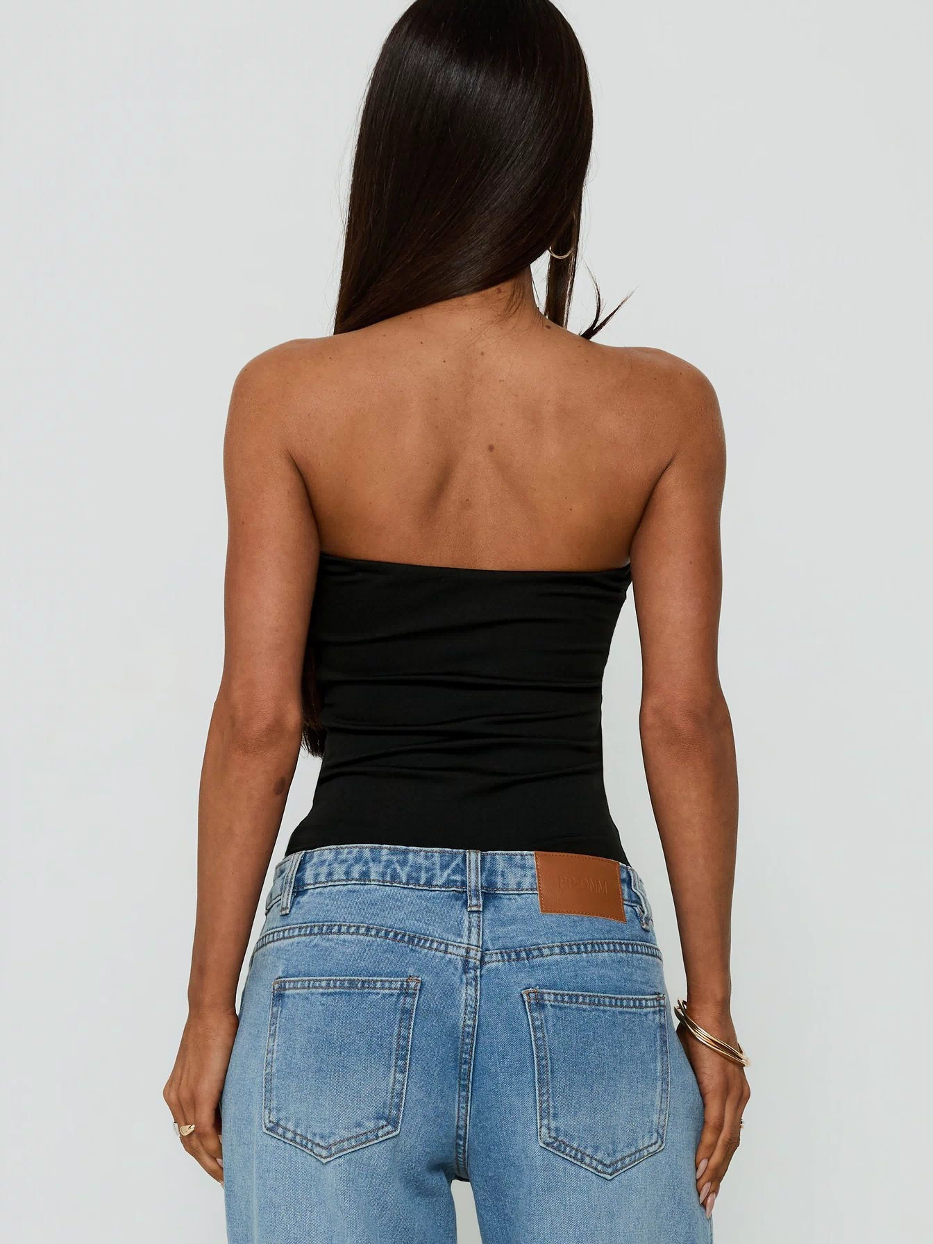 Designed with the Namari Strapless Bodysuit Black womens-bodysuit in sleeveless ruched style back view of model wearing Princess Polly