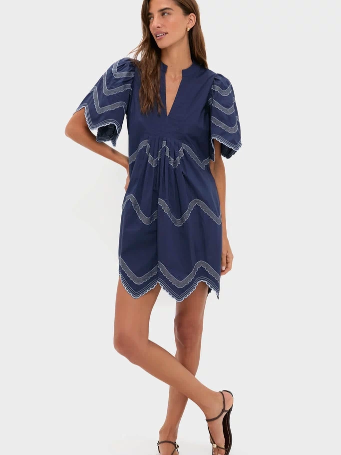Woman models the classic Navy Embroidered Weston Mini Dress with scalloped edges and intricate detailing, embodying effortless, high-end style perfect for fun, versatile occasions.