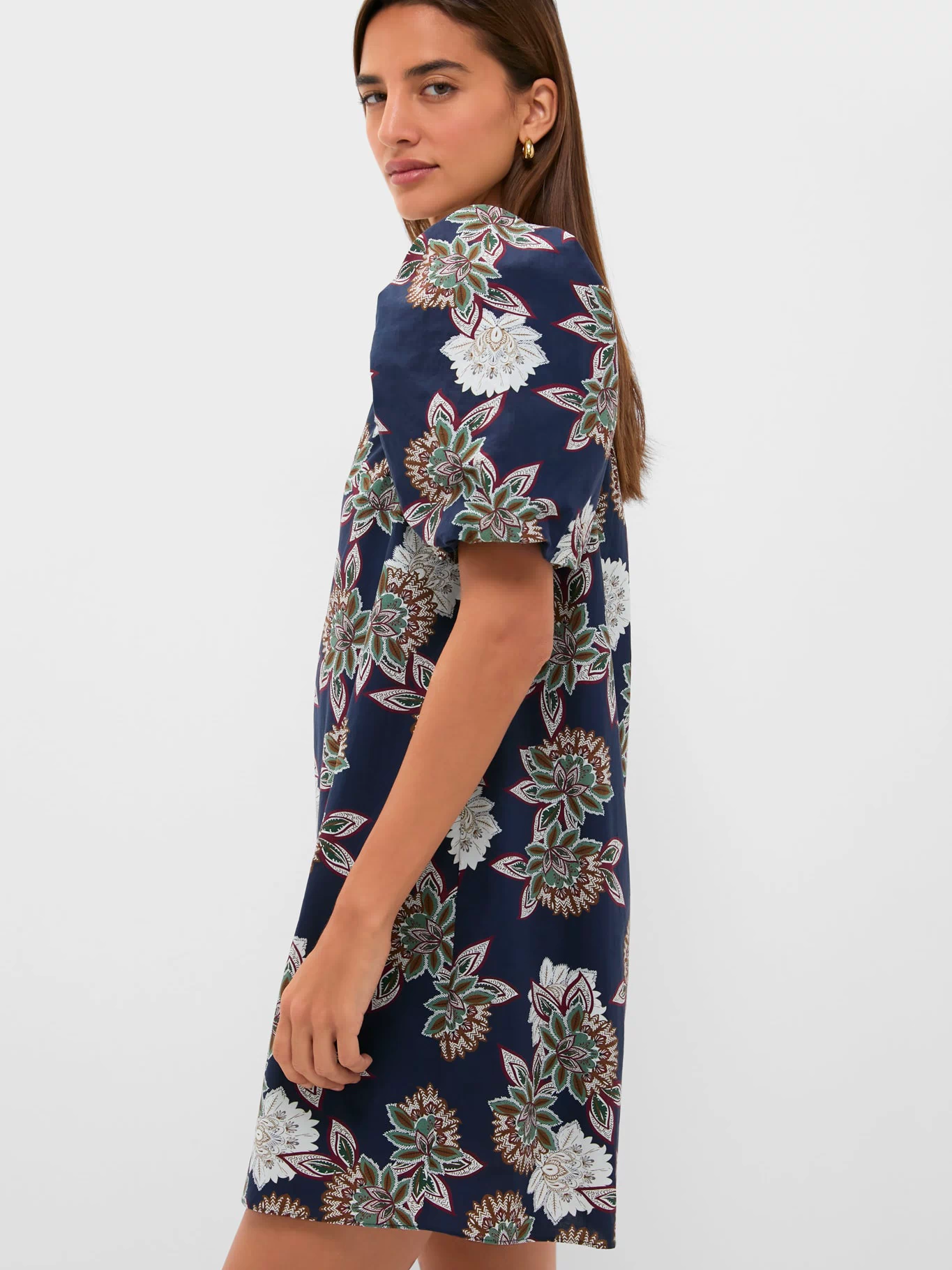 Young woman models the Navy Floral Mimi Mini Dress featuring puff sleeves and a ruffle collar, exuding classic, effortless style with a fun, high-end floral pattern.