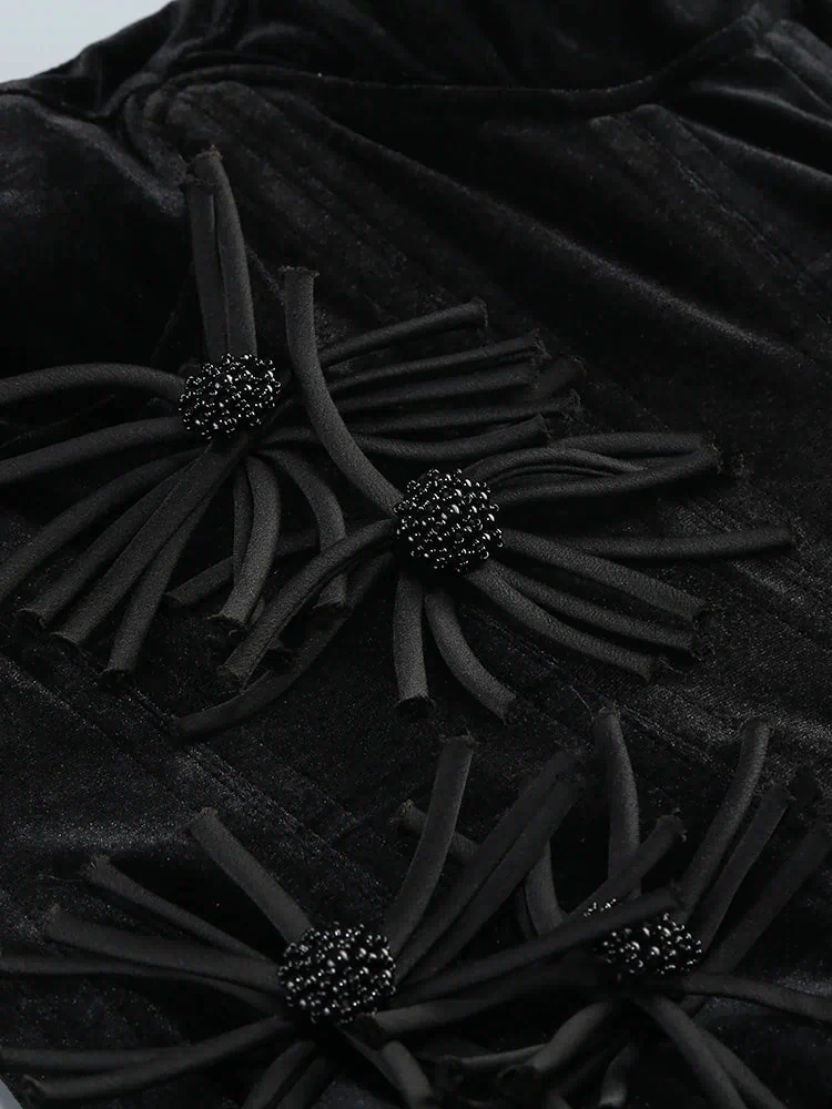 Black textured fabric with decorative black flowers and beads.