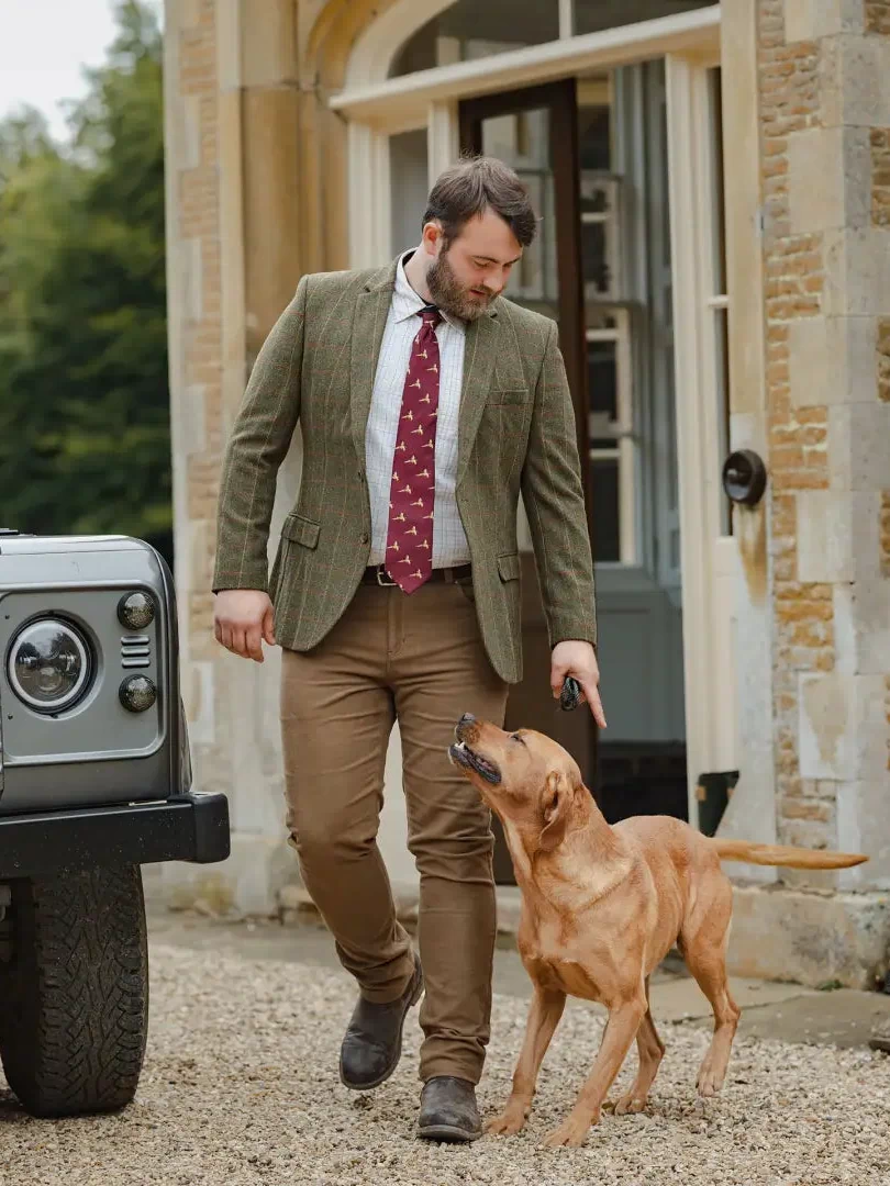 Man in Forest Heritage Tweed Blazer walking with a fox red Labrador outdoors