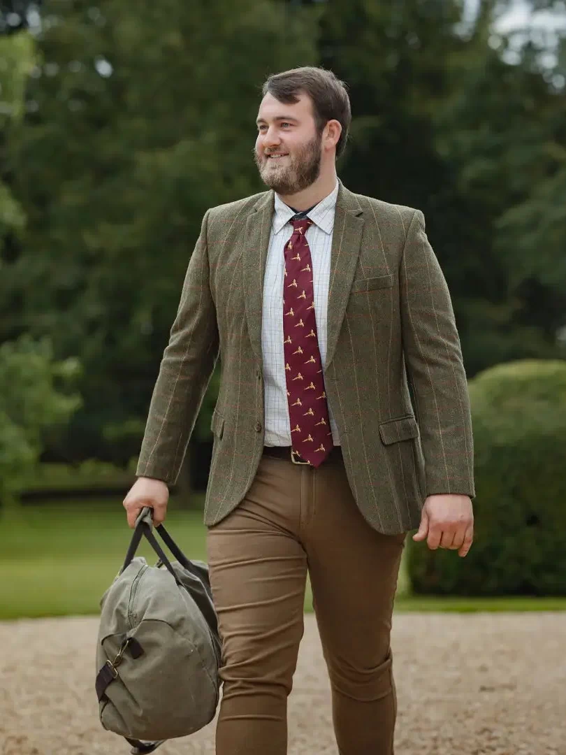 Man in forest heritage tweed blazer with plaid shirt and duffel bag, stylish look