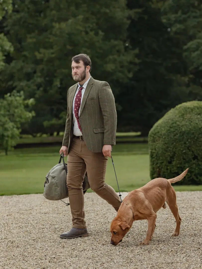 Man in Forest Heritage Tweed Blazer walking a brown dog on a leash outdoors
