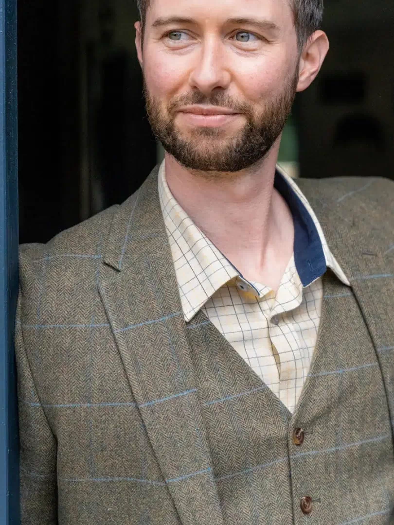 Man with dark hair in a wool tweed blazer over a plaid shirt showcasing style