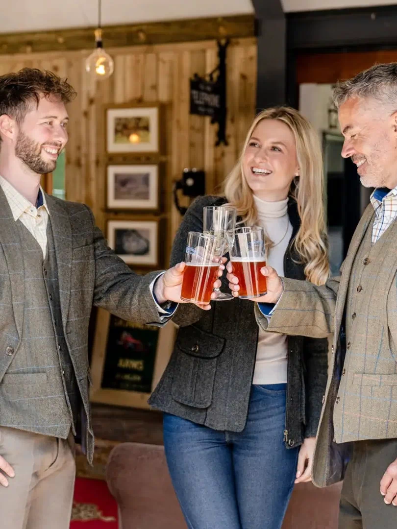 Friends toasting with beer in a pub, wearing a stylish wool tweed blazer