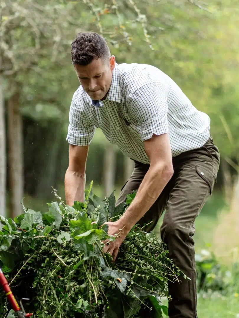 Man in a garden wearing a New Forest Premium short sleeved shirt, handling leafy plants