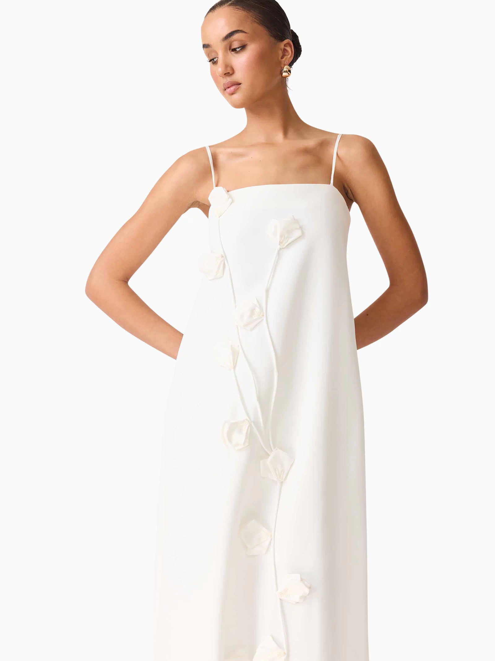 Brunette model wearing Nolana Floral Applique Gown in White close up posed shot
