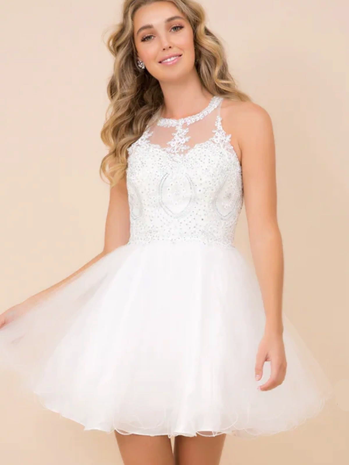A young woman poses against a beige background in a Short Babydoll Homecoming Dress with Beading, featuring a sheer embellished bodice and flared tulle skirt.