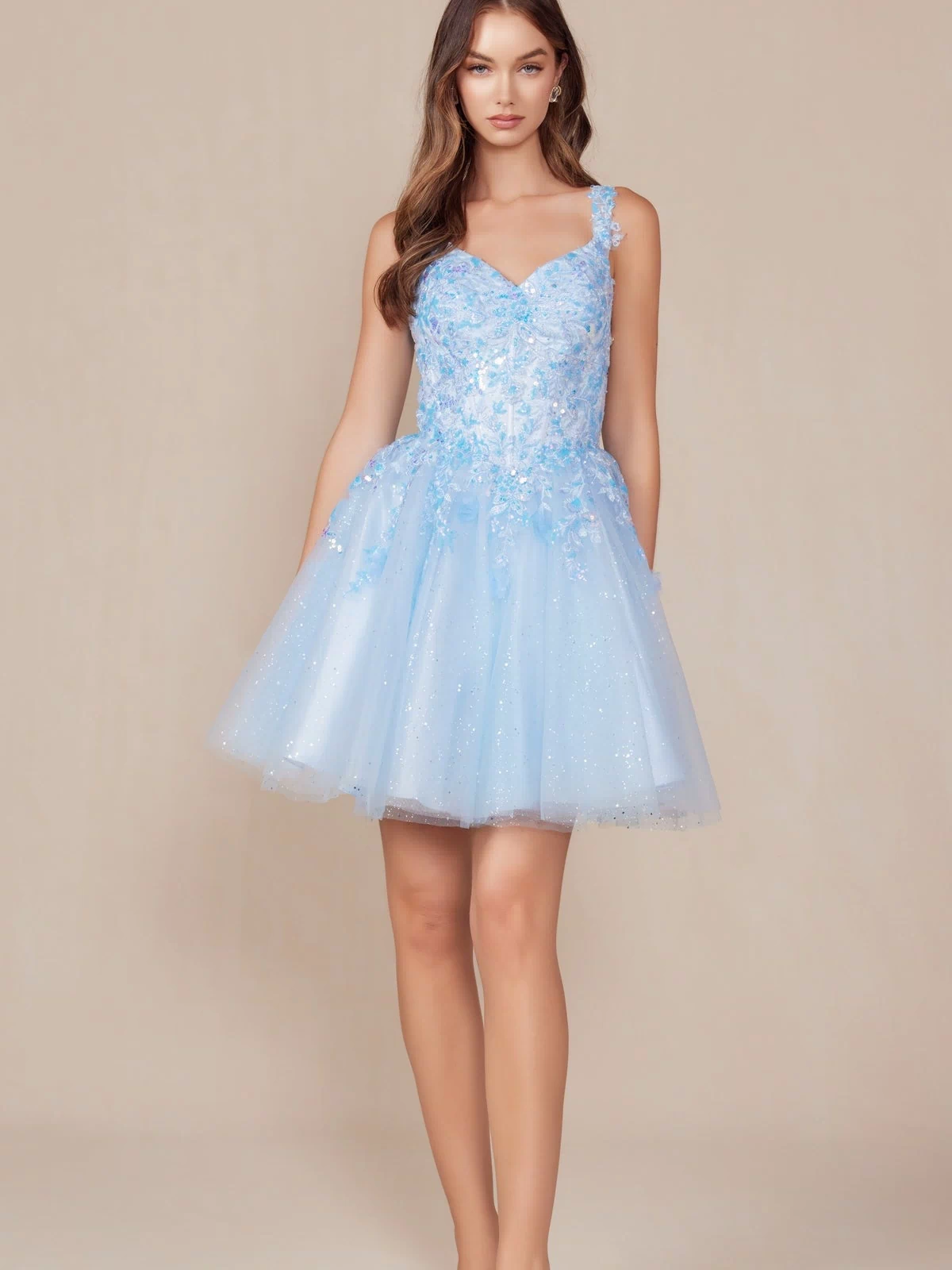A woman poses against a beige background in the Embroidered-Bodice Short A-Line Hoco Dress H846, featuring floral embellishments, a lace sweetheart bodice, sparkly tulle, and clear heels.