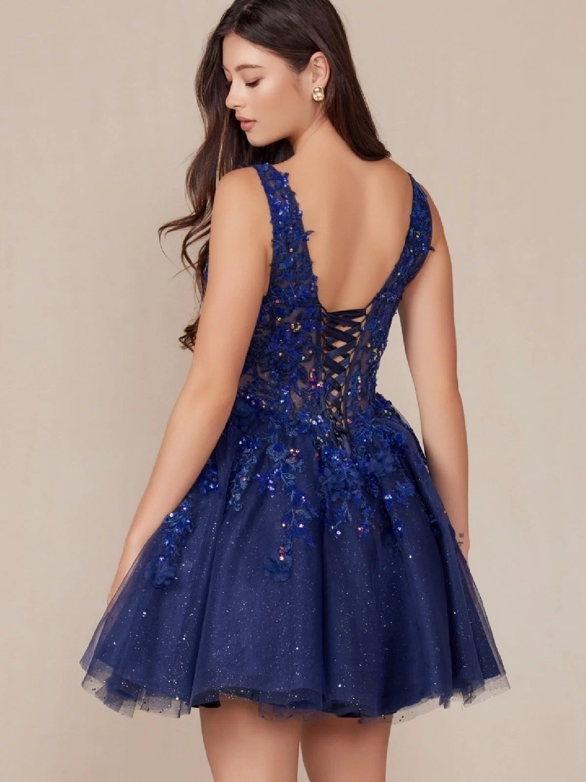 A woman models the Embroidered-Bodice Short A-Line Hoco Dress H846, a sleeveless navy blue party dress with a lace sweetheart bodice, floral appliqué details, and lace-up back, set against a neutral background.