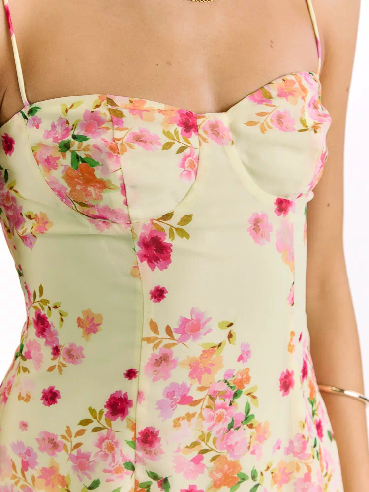 Close-up of the yellow floral mini dress's bustier bodice with structured cups, seaming, and thin spaghetti straps