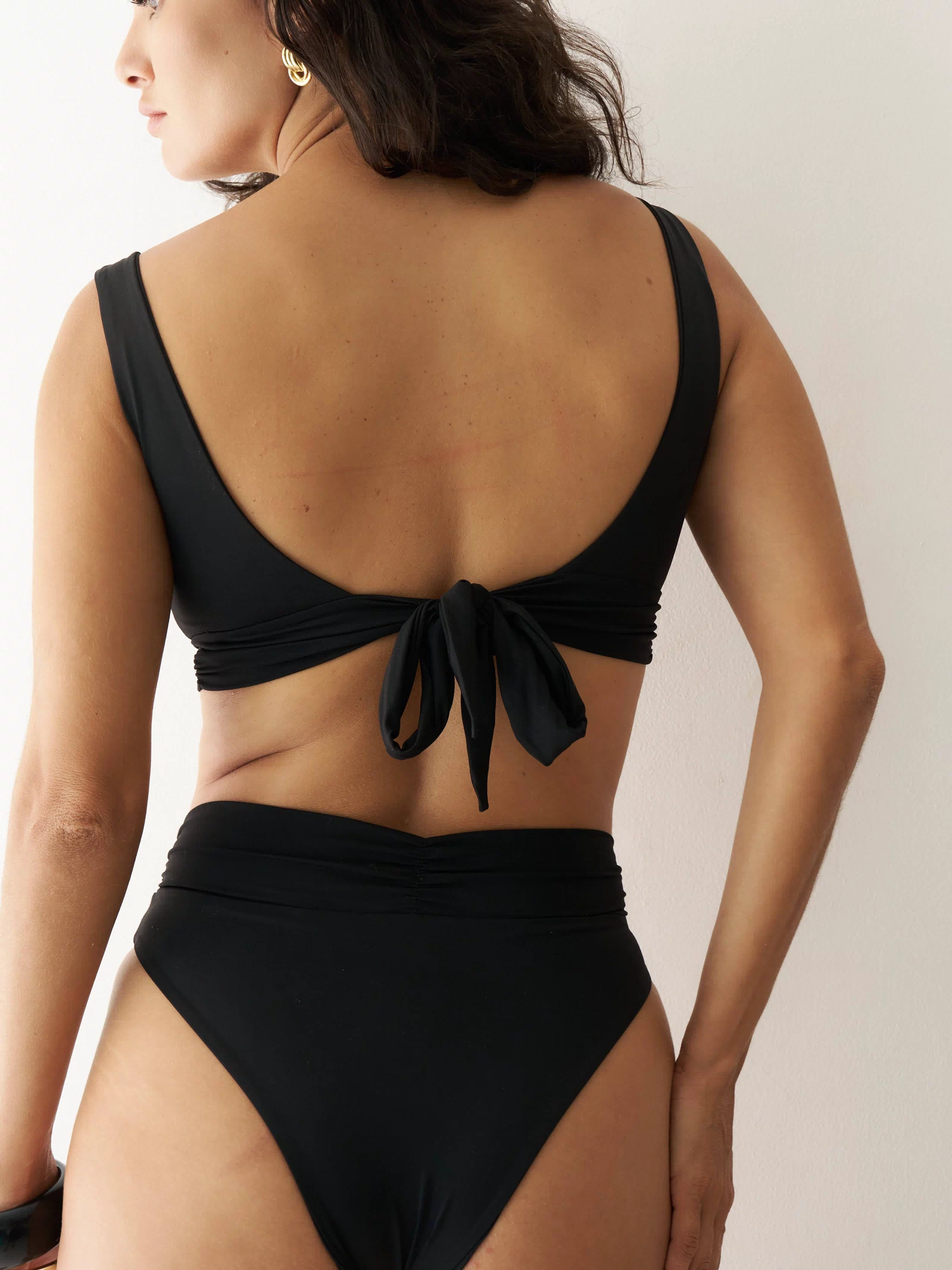 Black RIOT SWIM Pico Top, a stylish swim top shown from the back view with adjustable straps.
