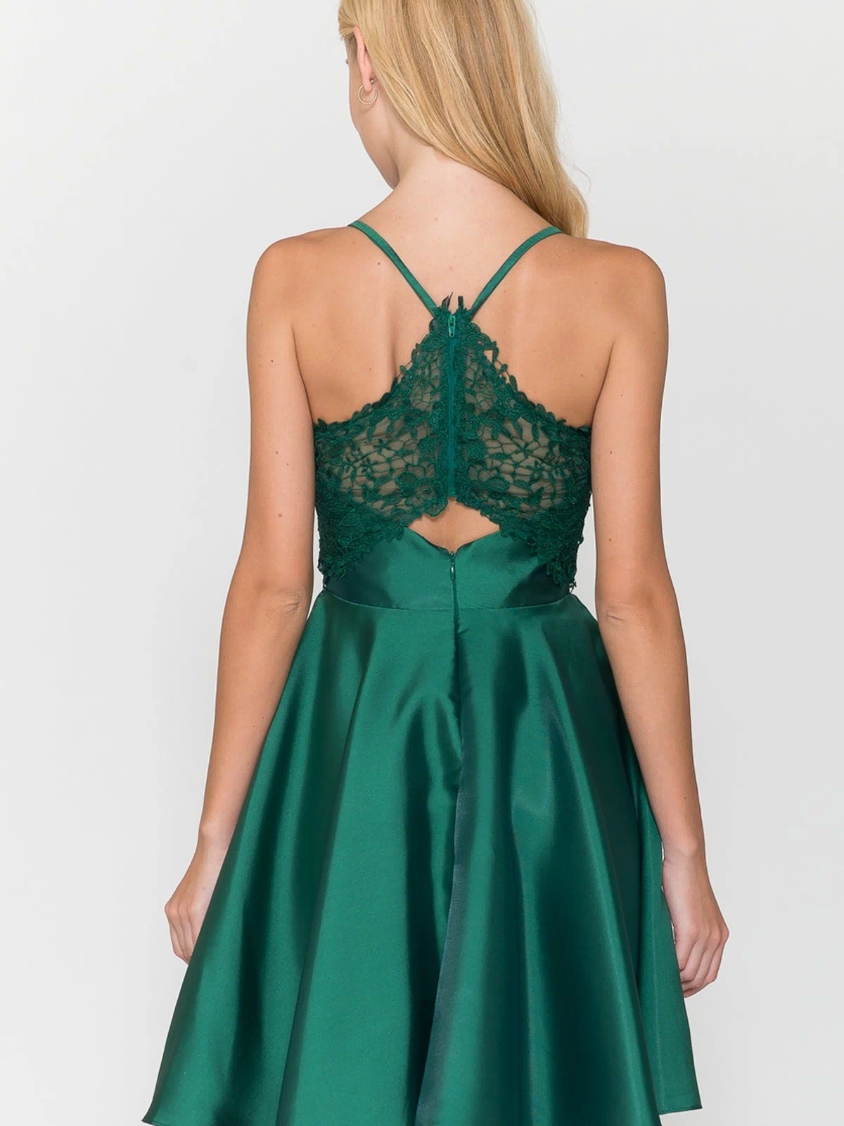 A woman is seen from behind wearing the Lace-Back Short A-Line Homecoming Dress 8698, featuring a green flared satin skirt and lace detailing on the back, set against a plain background.