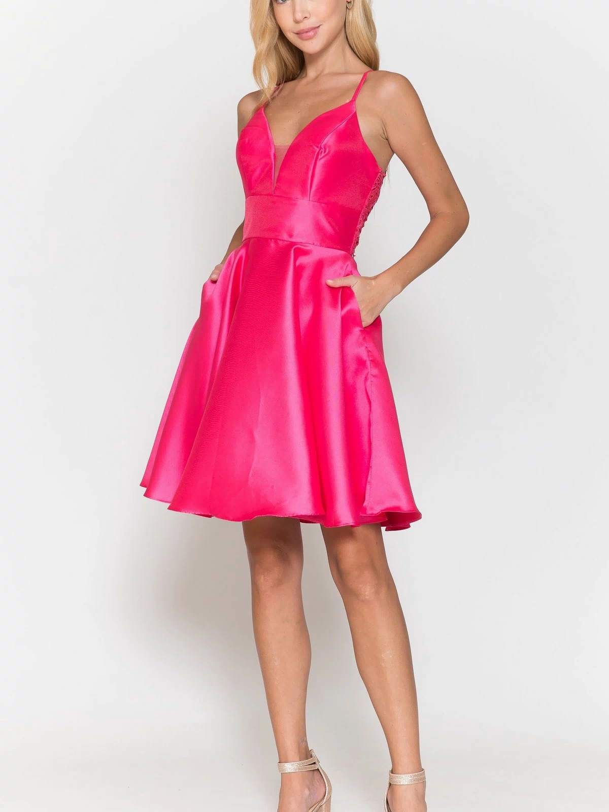 A woman models the Lace-Back Short A-Line Homecoming Dress 8698—sleeveless, hot pink satin with a V-neckline and flared skirt—paired with heels against a white background.
