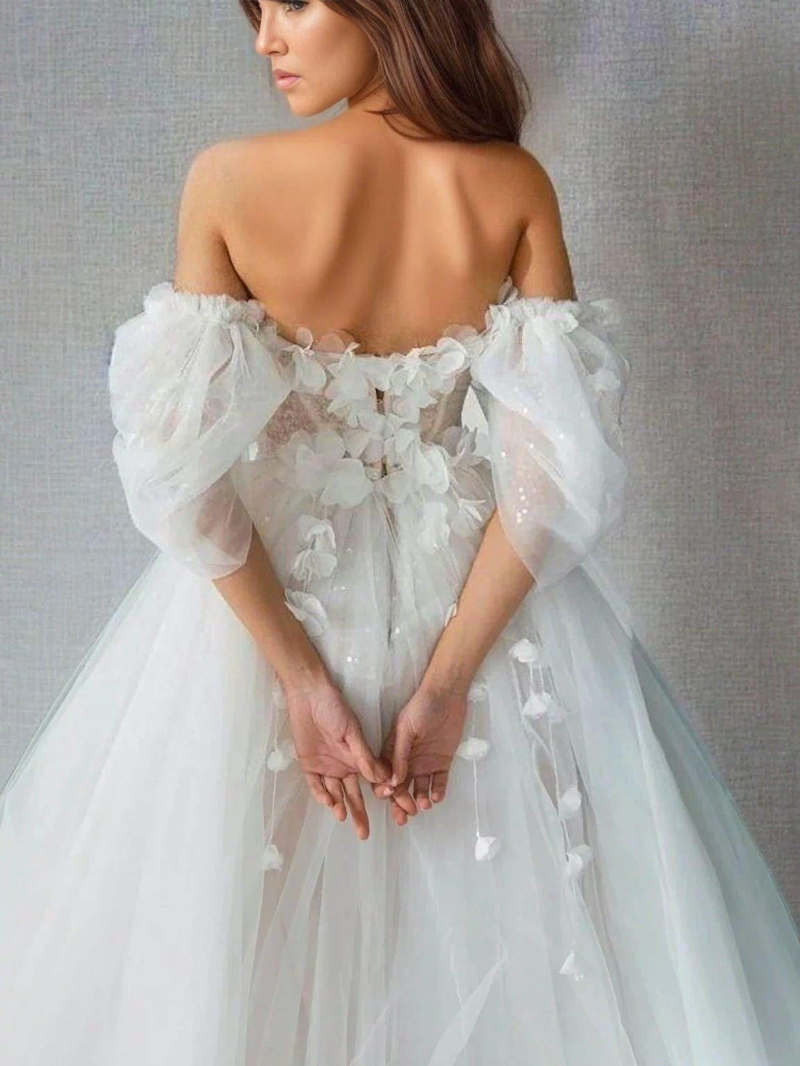 Back view of the SHERYL wedding dress showcasing its off-the-shoulder sleeves. and 3D flowers.
