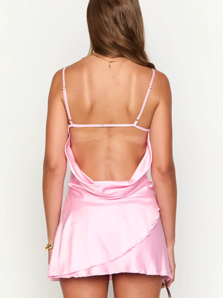 Rear view of a pink satin mini dress with a low cowl back, thin adjustable spaghetti straps, and a layered ruffled hem
