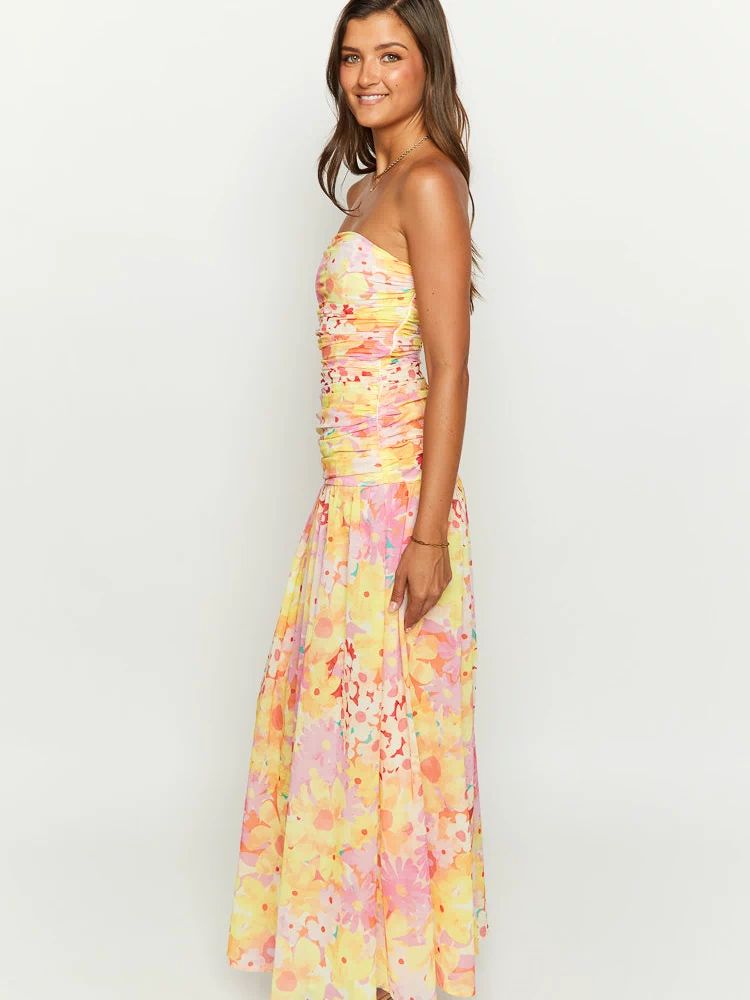 Side profile of a yellow floral strapless maxi dress showing the ruched bodice and full, flowing skirt