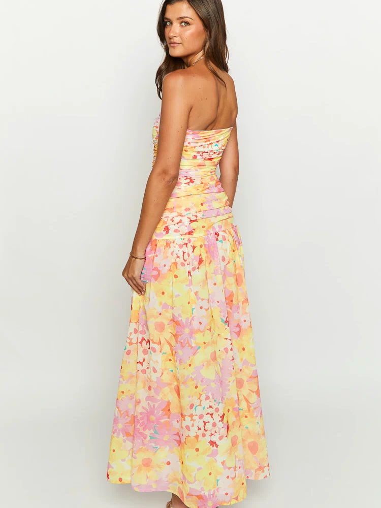 Side view of a yellow floral print strapless maxi dress with a ruched bodice and flowy skirt