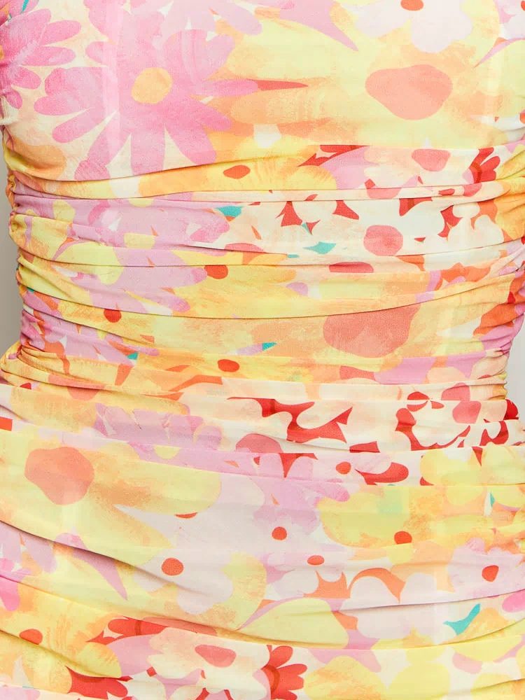 Close-up of the ruched detail on a yellow floral print strapless maxi dress with pink, orange, and red flowers