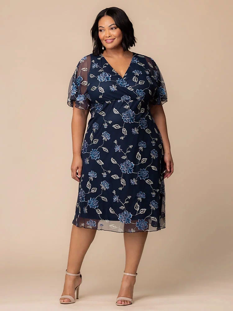 Sonnet Embroidered Midi Cocktail Dress in Navy Blue Blooms  Plus size model wearing navy blue embroidered mesh midi dress with V-neckline and sheer flutter sleeves, ideal for weddings, parties, or formal occasions.
