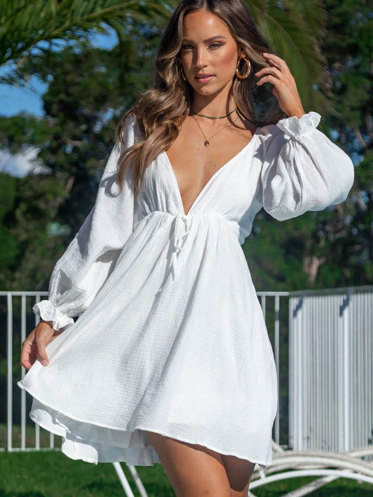 White textured mini dress with deep V-neck, long balloon sleeves, and ruffled cuffs