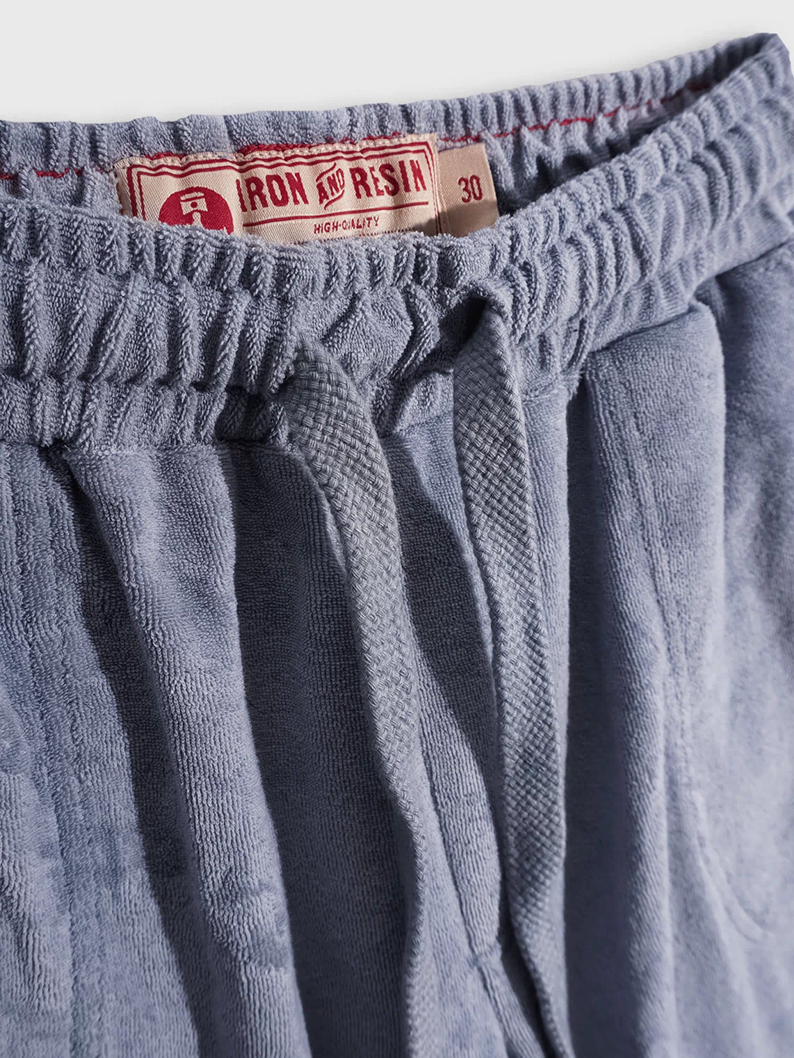 Blue drawstring shorts with an Iron and Resin label, size 30, featuring a textured fabric and elastic waistband.
