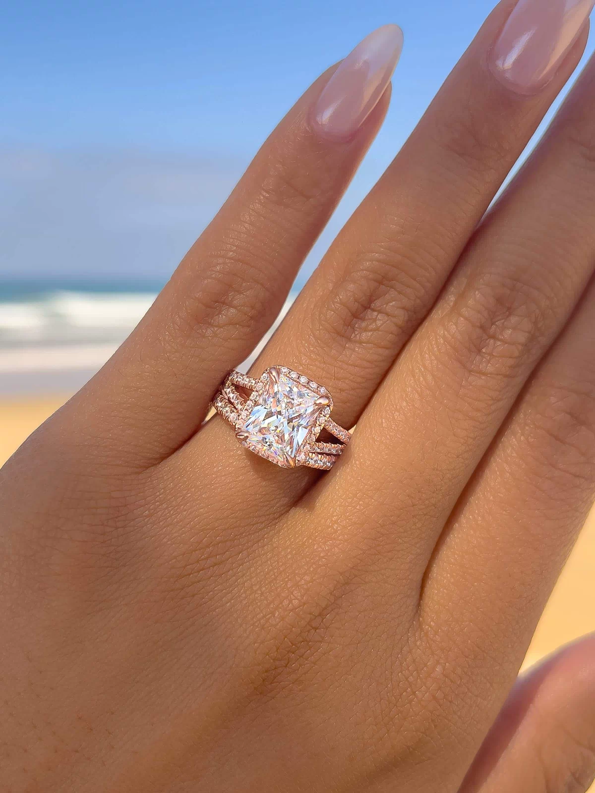 classic rose gold wedding ring set with 3.5 carat radiant cut center stone on female model with ocean in background