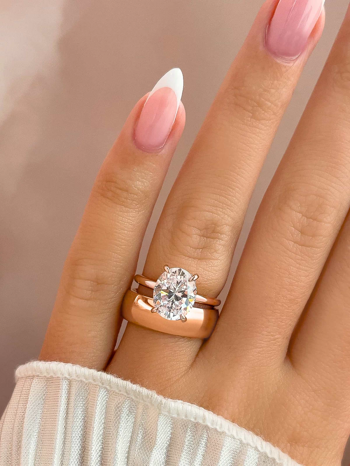 stunning rose gold affordable unisex horizon wedding band on model's hand with oval cut rose gold engagement ring