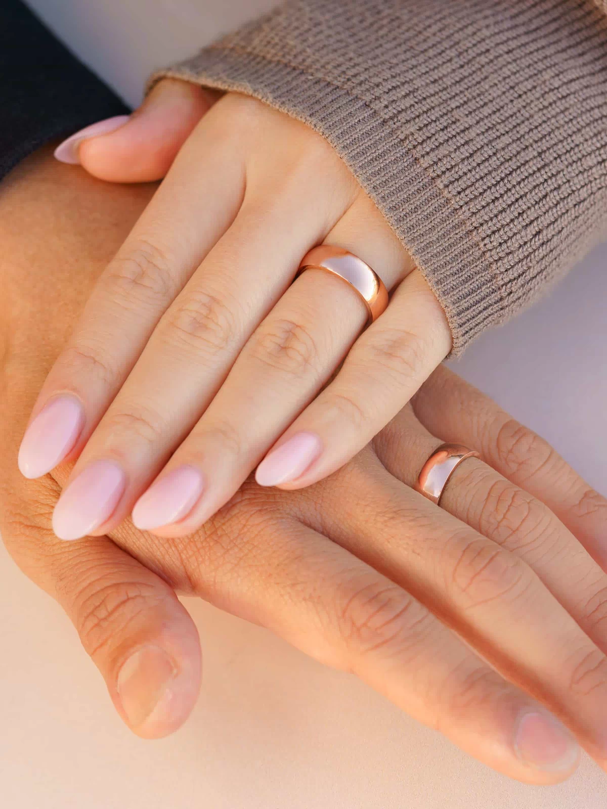 affordable unisex rose gold Horizon wedding bands shown on hands of couple 