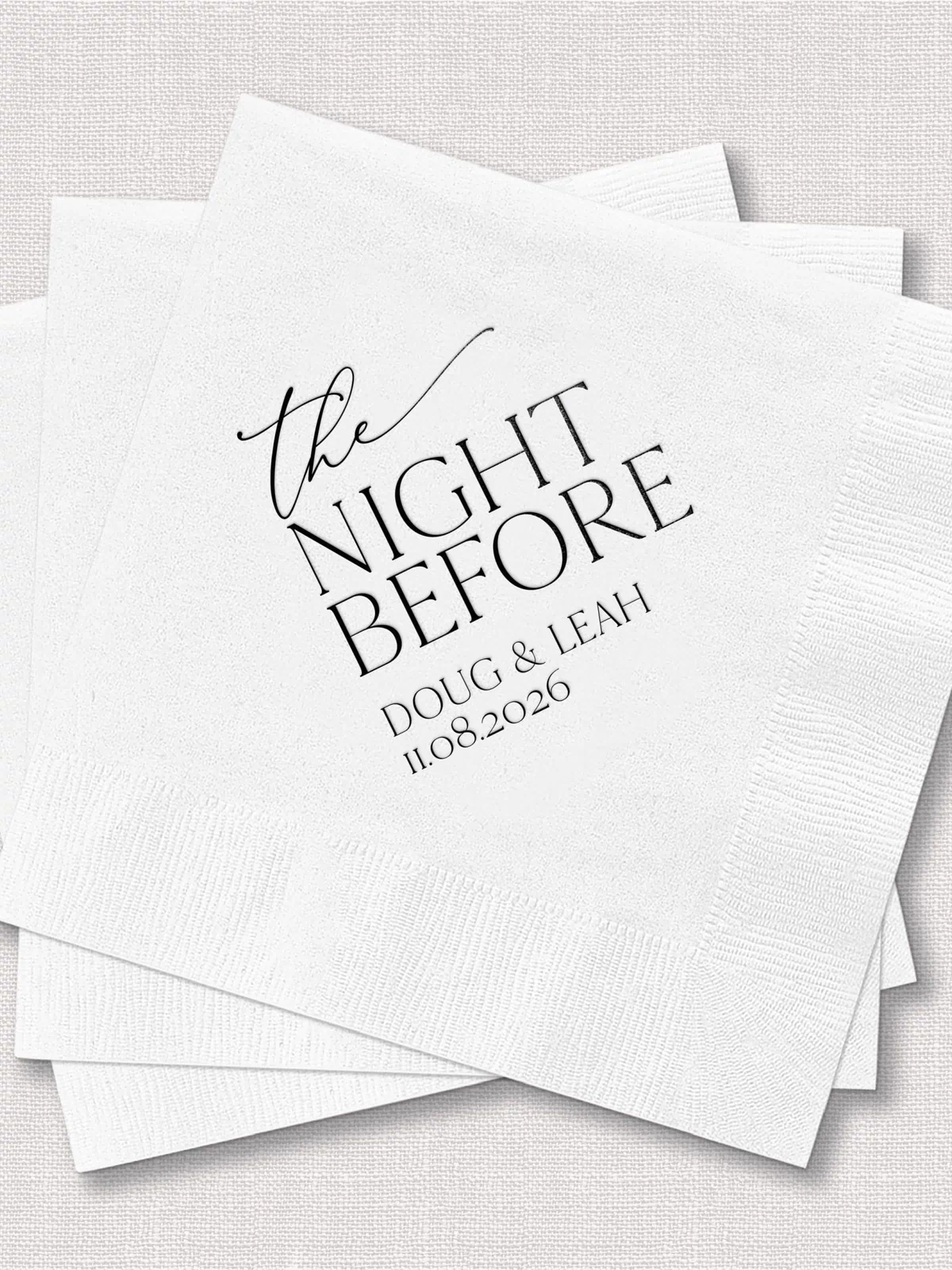 Stack of white personalized napkins with "the NIGHT BEFORE" text and couple names and date in foil stamped design.
