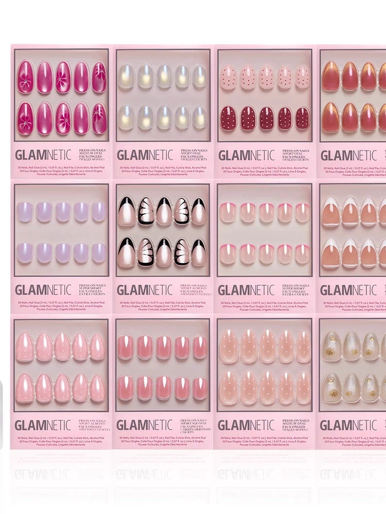 Fifteen boxes of glamnetic’s The Spring Edit Collection press-on nails are arranged in a grid above a bottle of glamnetic brush-on nail glue, all displayed on a white background.