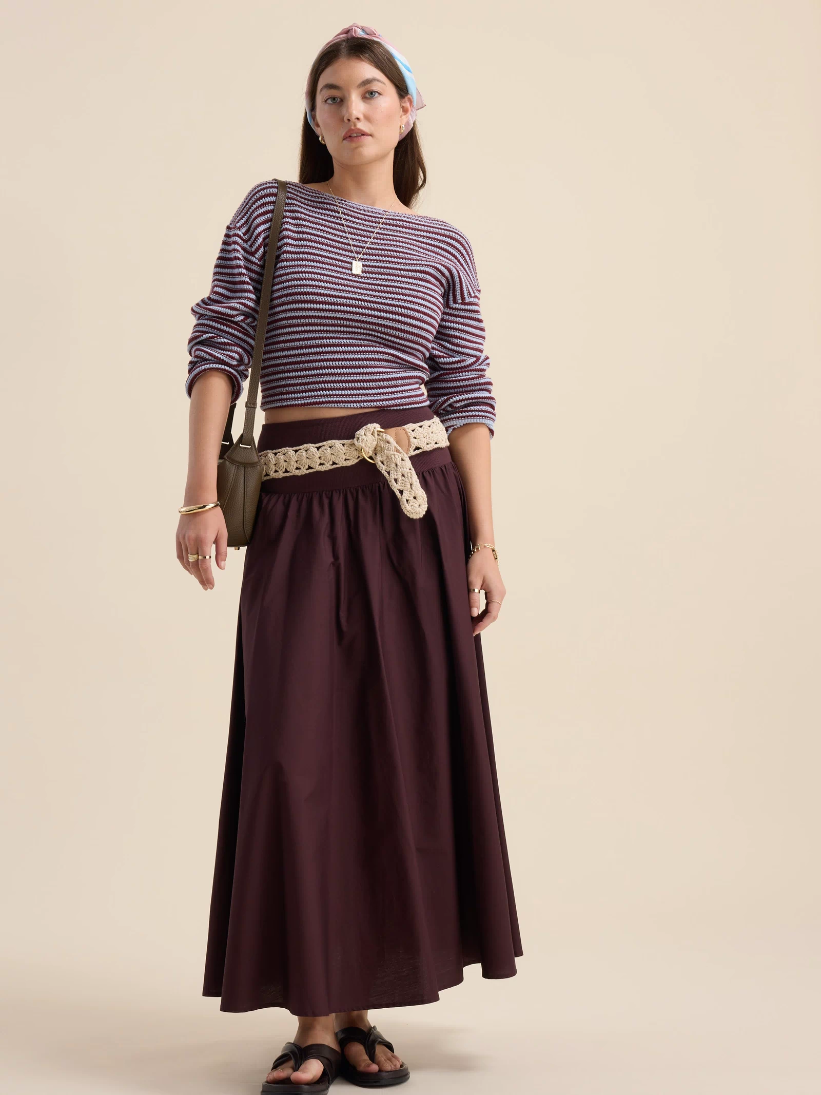 Woman in striped sweater, The Ultimate Skirt by Max, sandals, and headband against beige background.