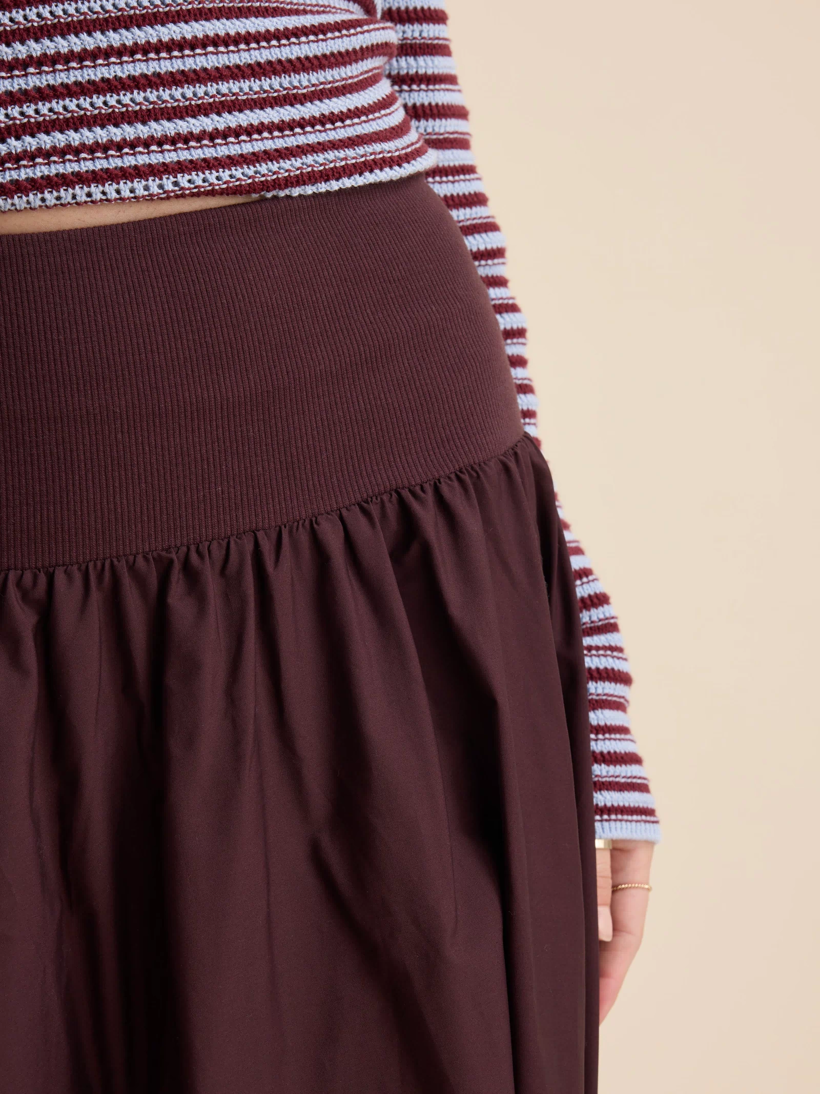Close-up of a person in a Max striped sweater and The Ultimate Skirt with a high waist.