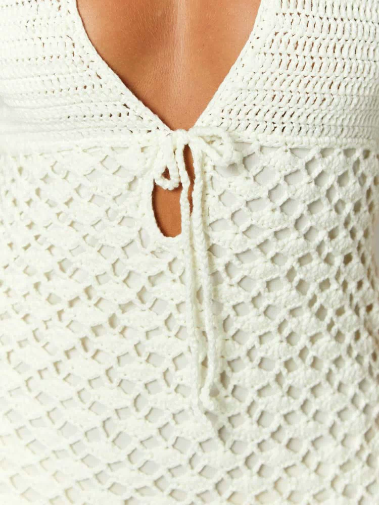 Close-up of the cream crochet mini dress with a V-neckline, central tie-front, and open net-like pattern