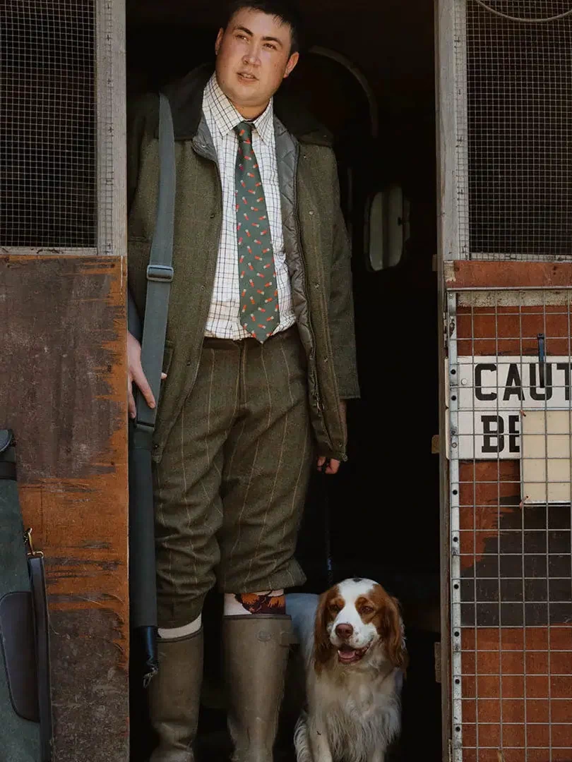 Man in a green suit with his Spaniel dog showcasing a stylish English made tweed shooting jacket