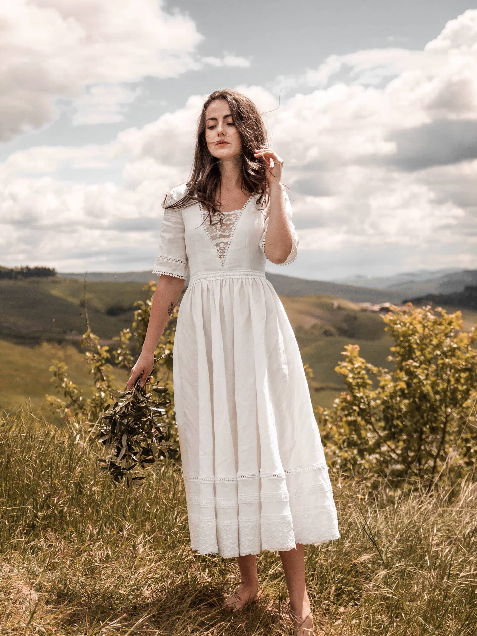 Full-length front view of the Under the Tuscan Sky ivory linen wedding dress in the countryside