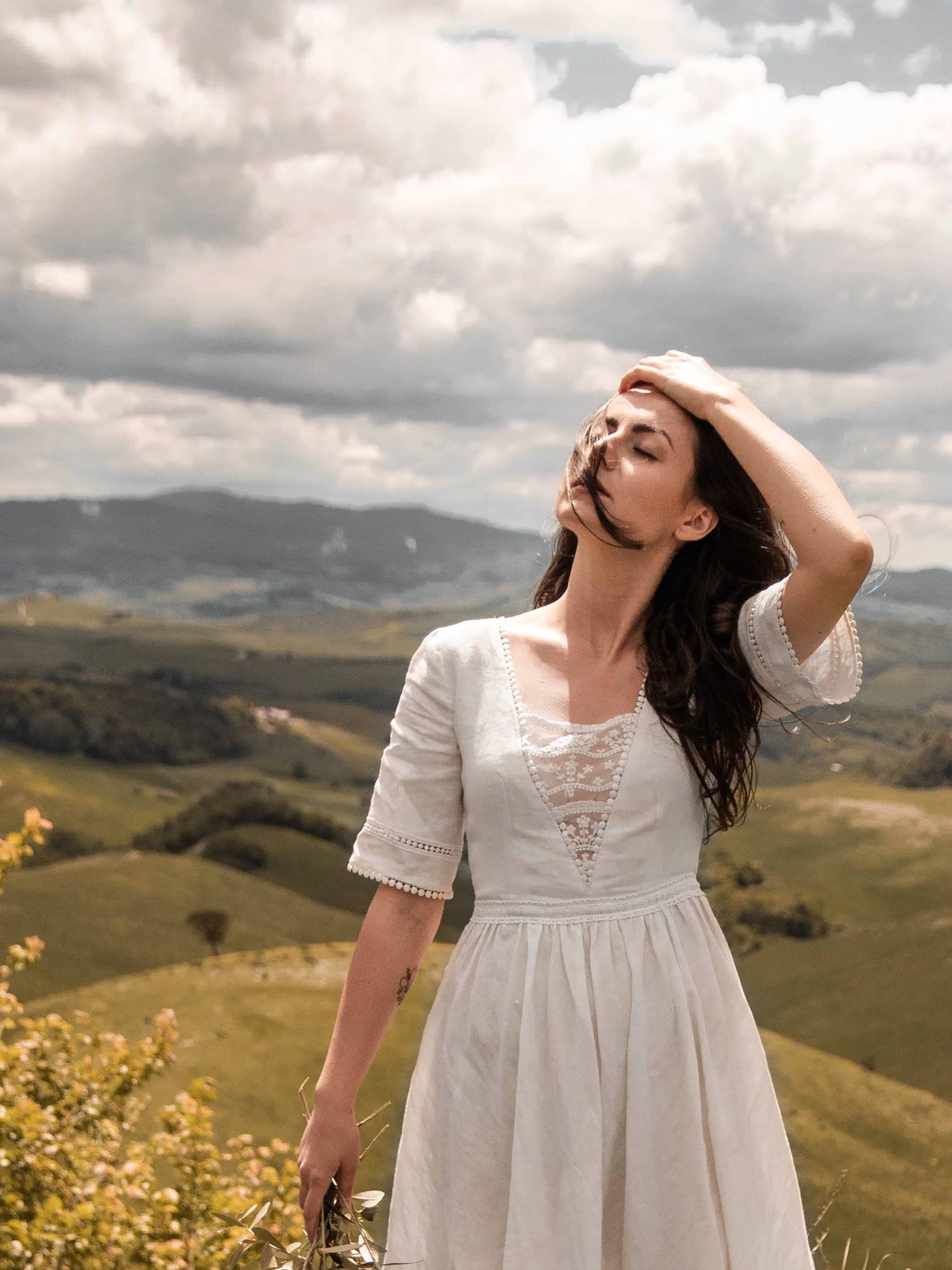 Three-quarter view of the Under the Tuscan Sky ivory wedding dress against the Tuscan hills