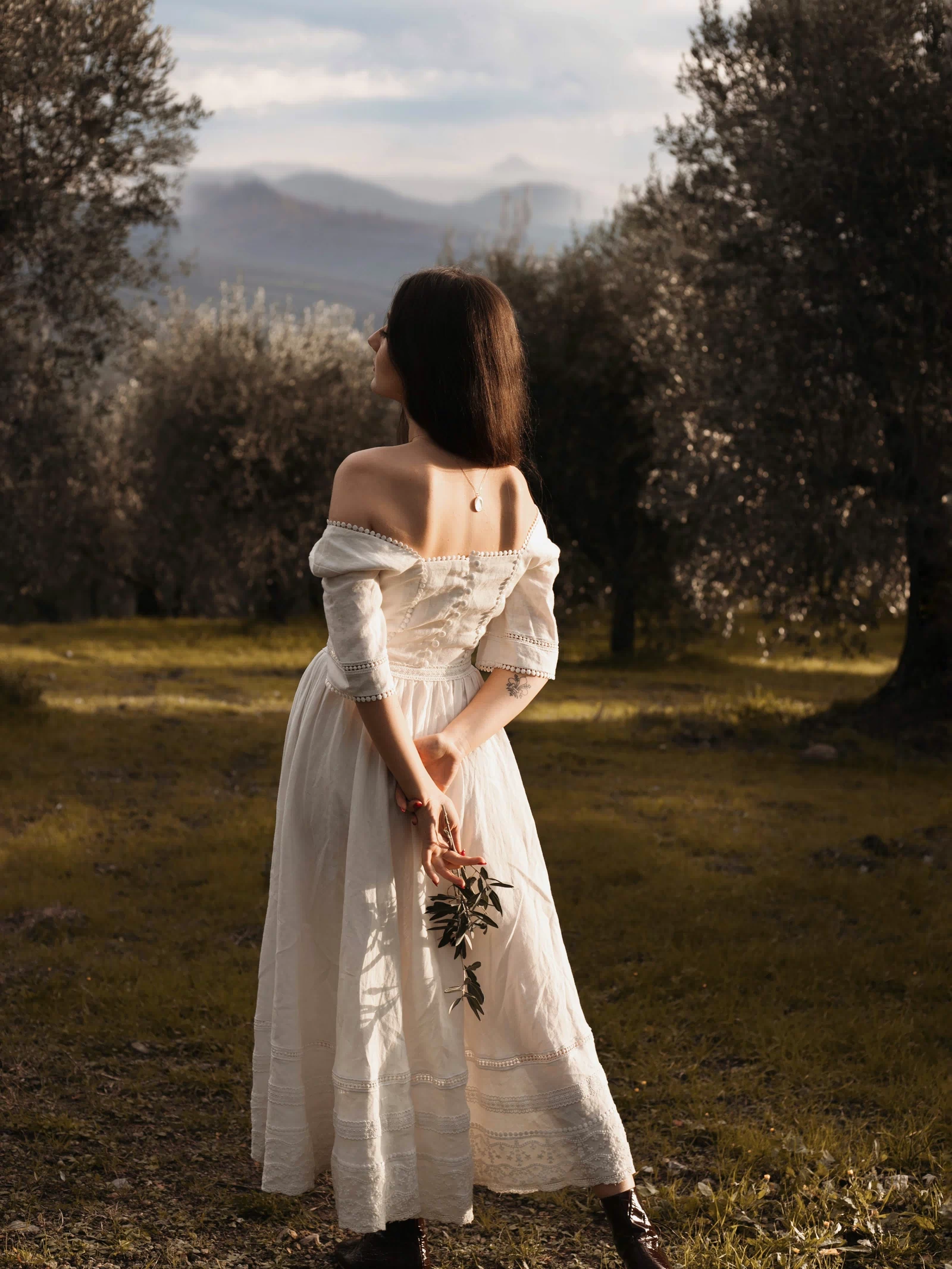 Back view of the Under the Tuscan Sky ivory linen wedding dress photographed among olive trees