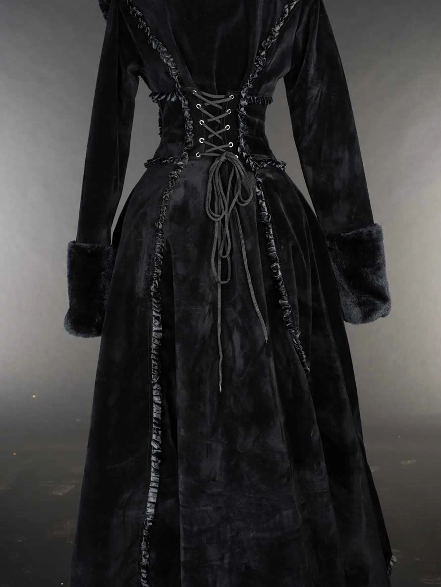 Back view of women's black velvet winter coat with satin details and faux fur trim showing adjustable corset style lacing 