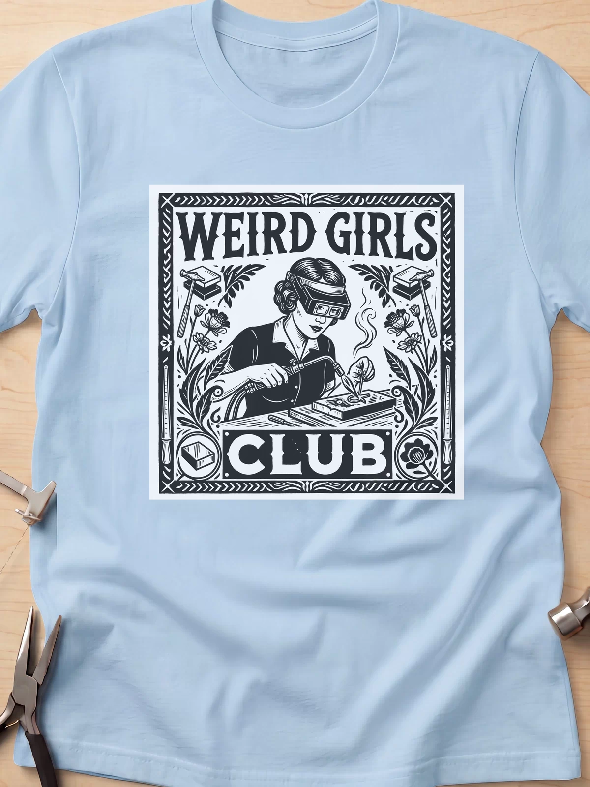 Weird Girls Club funny metalsmith t-shirt in Light Blue, flat lay with jeweler's tools