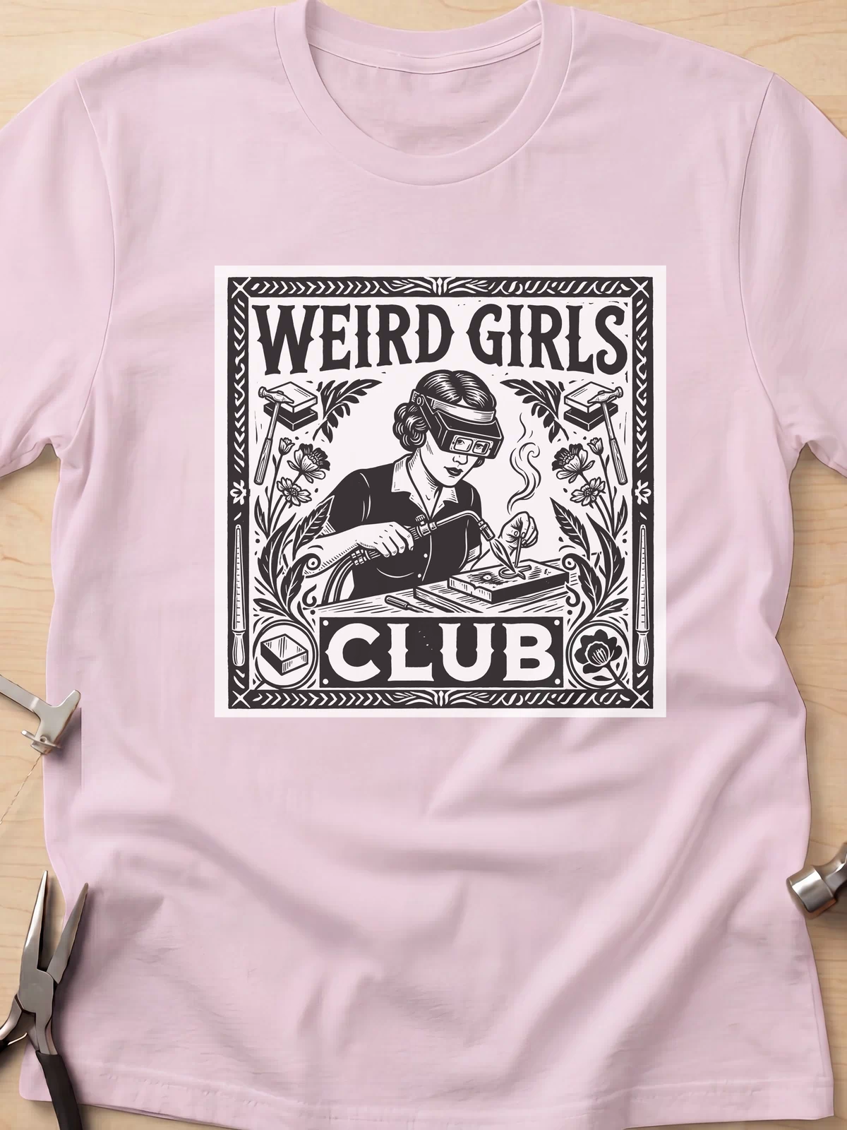Weird Girls Club funny metalsmith t-shirt in Light Pink, flat lay with jeweler's tools