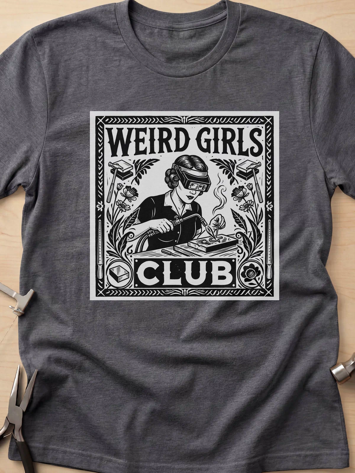 Weird Girls Club funny metalsmith t-shirt in Dark Heather Grey, flat lay with jeweler's tools