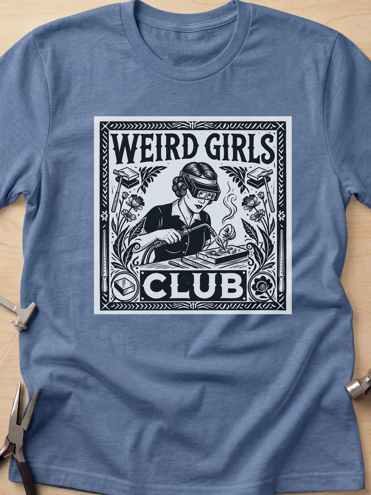 Weird Girls Club funny metalsmith t-shirt in Heather Indigo, flat lay with jeweler's tools